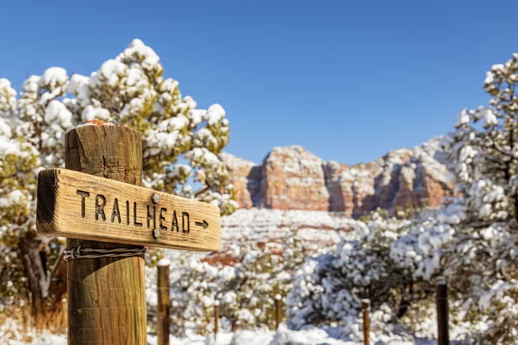Trailhead sign with Sedona's snow covered red rocks in the background