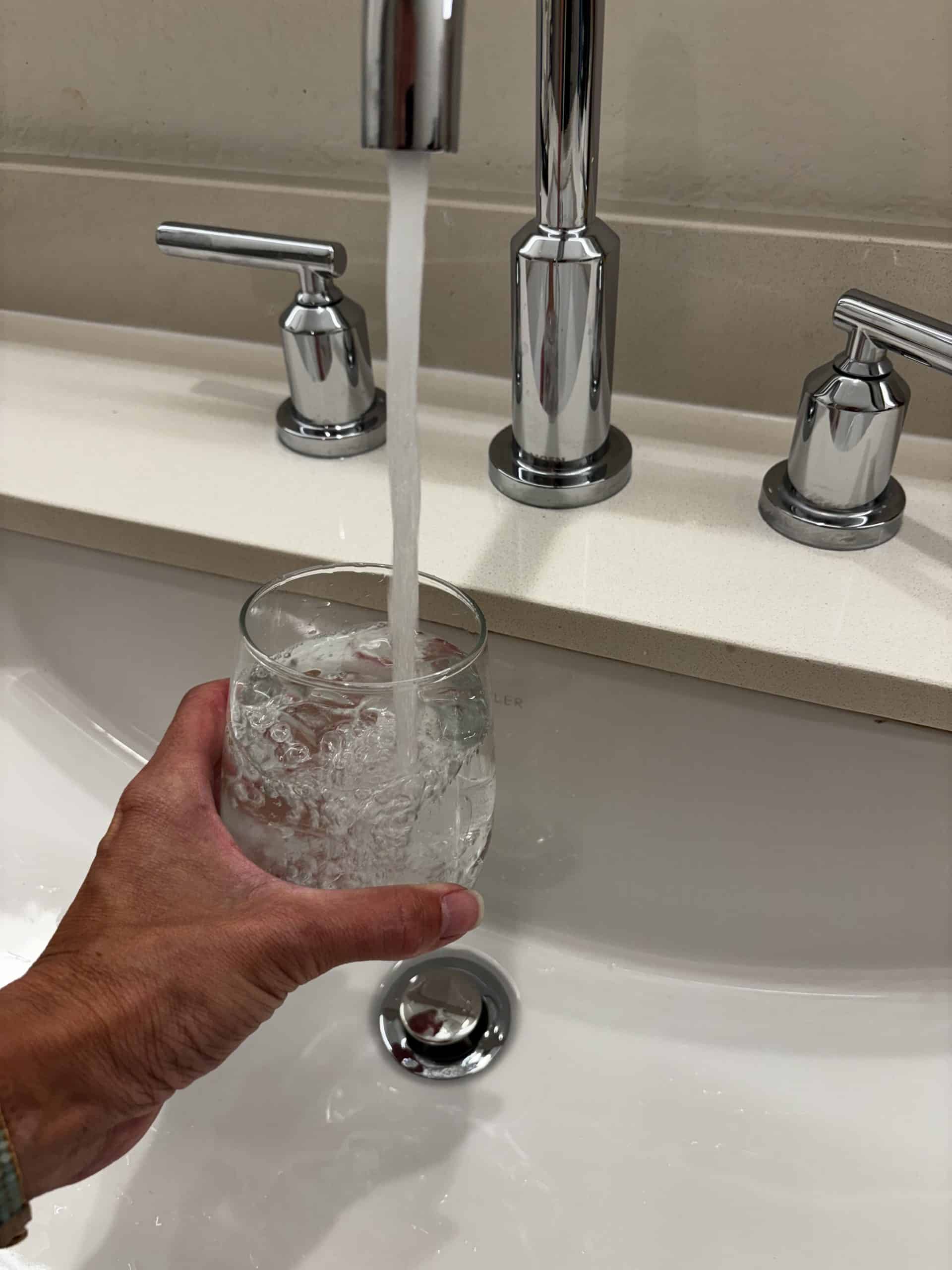 A glass of water being filled from a tap