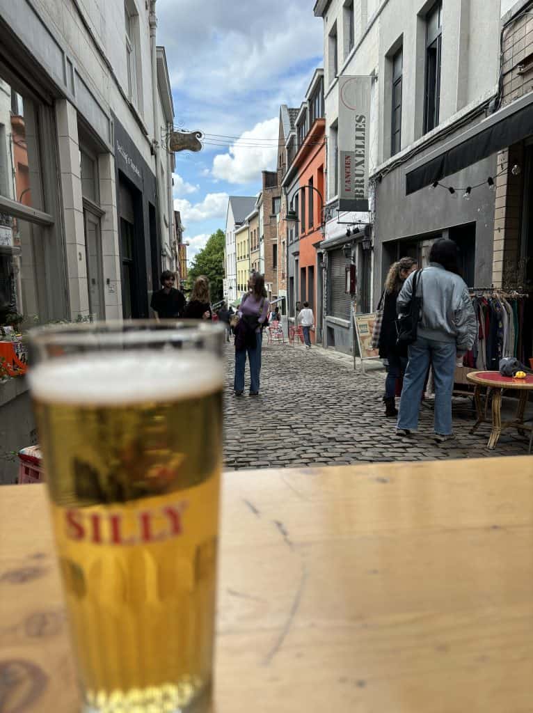 A Belgian beer in the foreground and a cobblestone street behind it.