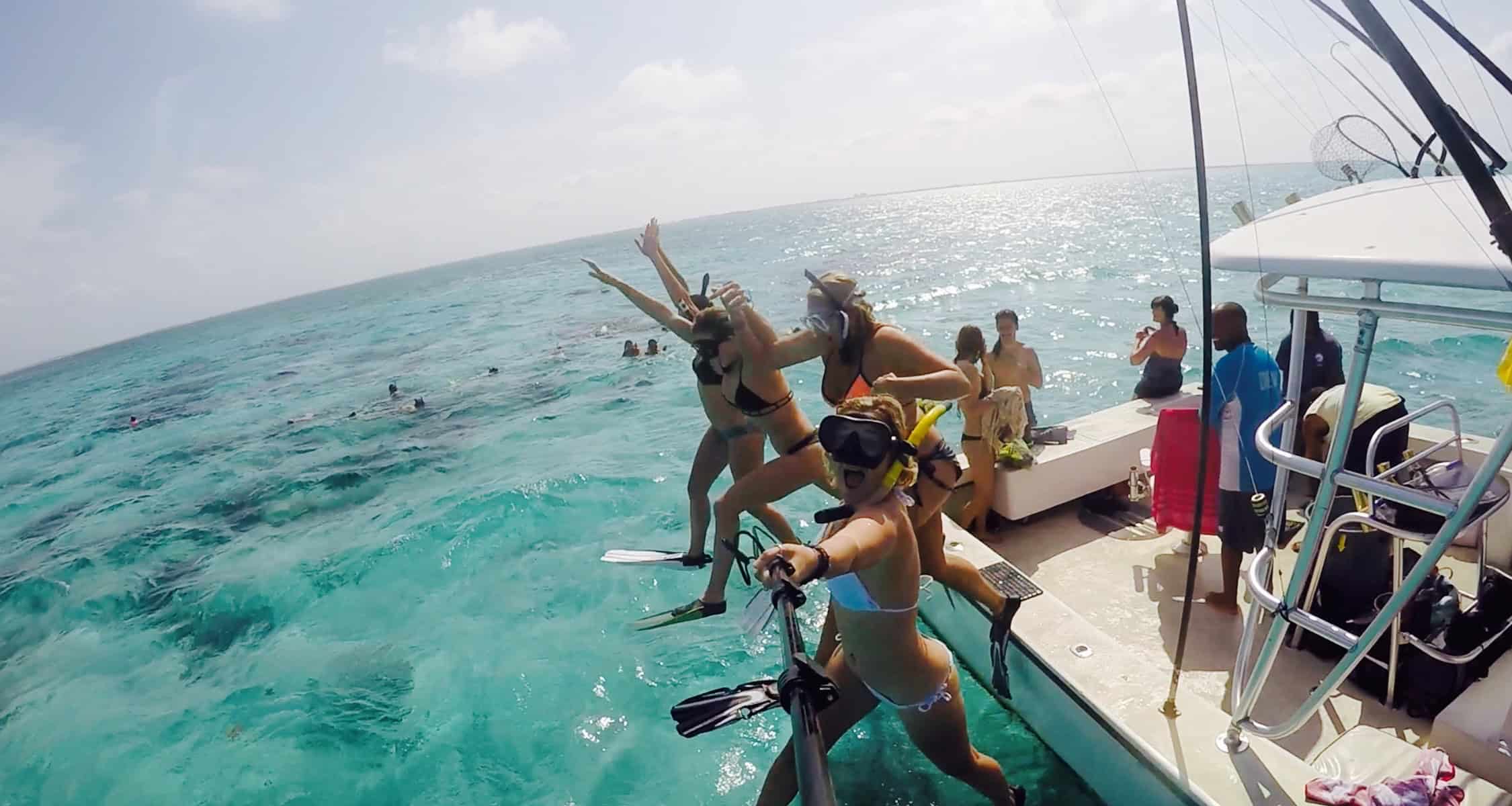 Four girls jumping into the water at Grand Cayman's Stingray City Deep