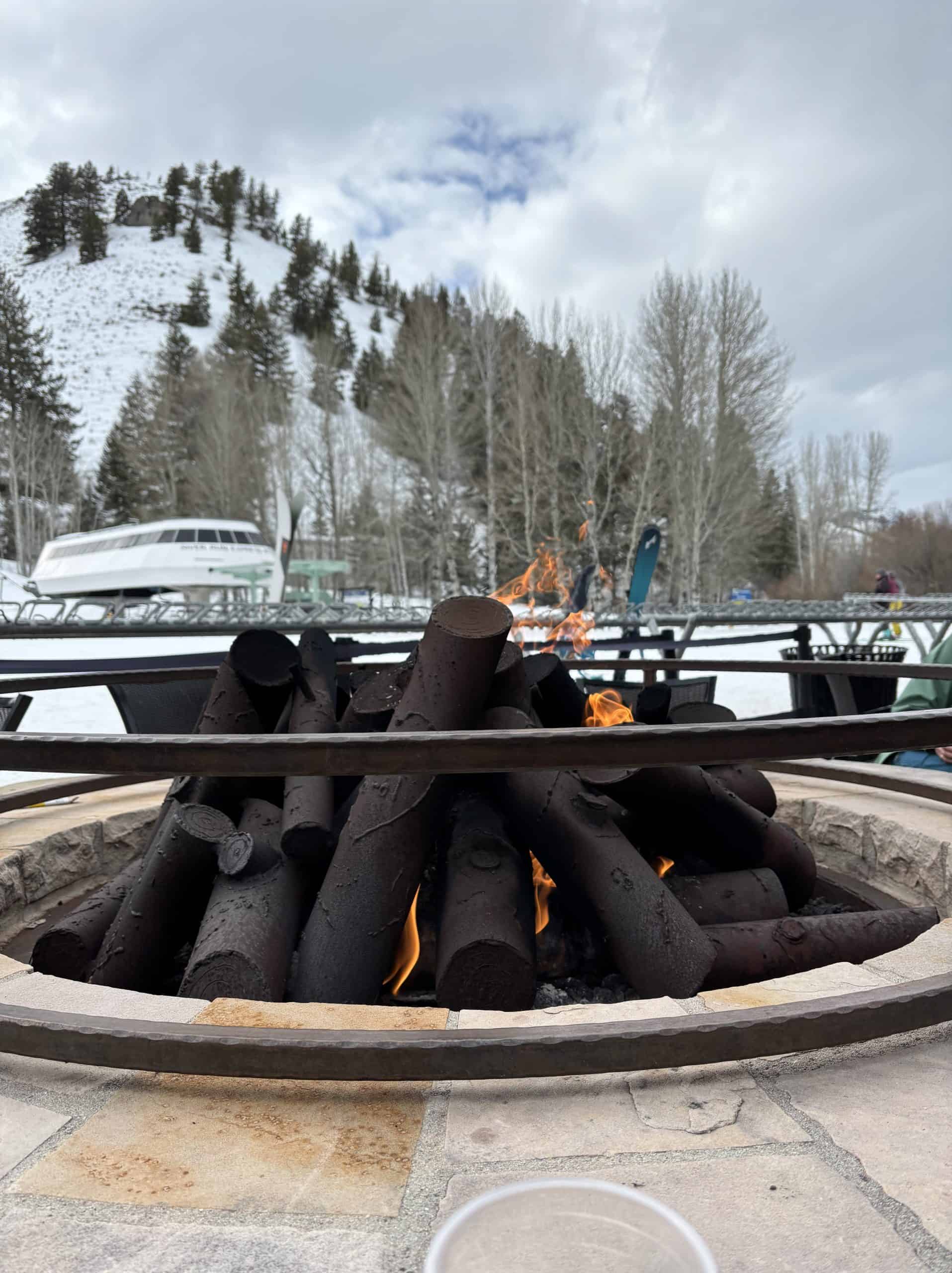 A lit gas fireplace at the base of a ski mountain in the winter